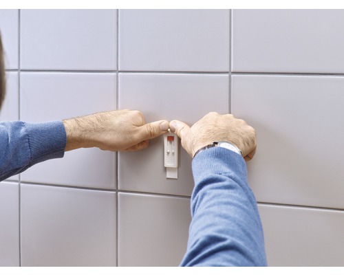 Man bevestigt een vochtsensor aan de wand