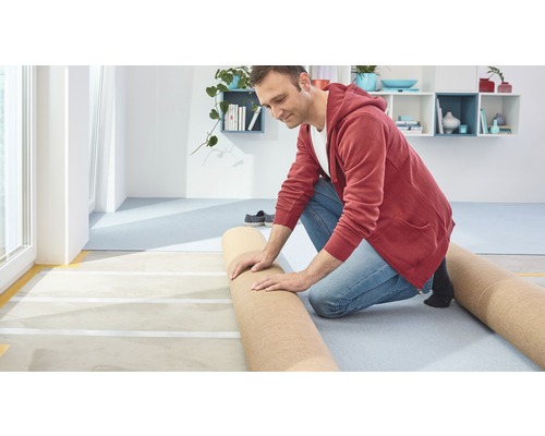 Man legt vloerbedekking in een heldere kamer.