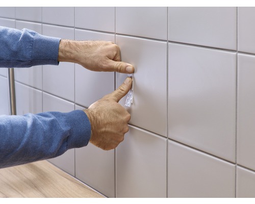 Een plakstrip aanbrengen op een betegelde muur