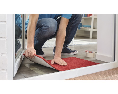 Man legt een rood tapijt in de kamer.