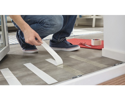 Iemand gebruikt afplakband om een vloer af te plakken ter bescherming.