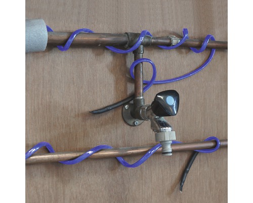 Installatie van koperen buizen met een kraan en blauwe buisverwarming.