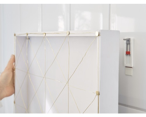 Witte wandplank met goudkleurige draaddecoratie