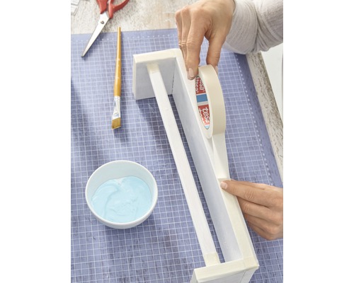 Knutselscène met handen, afplakband, kwast, verf en schaar op een snijmat