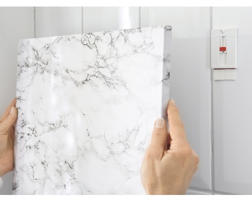 Decoratieve folie met marmerpatroon wordt op een badkamermuur aangebracht.