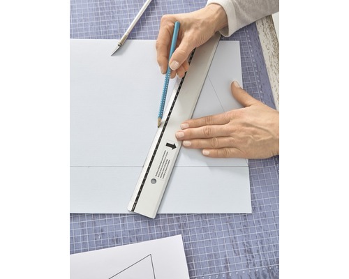 Persoon die met een potlood en een liniaal op een snijplank een lijn op een stuk papier tekent