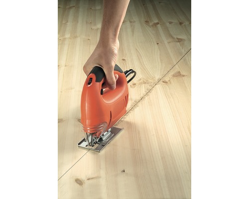 Persoon zaagt een houten plank langs een lijn met een decoupeerzaag.