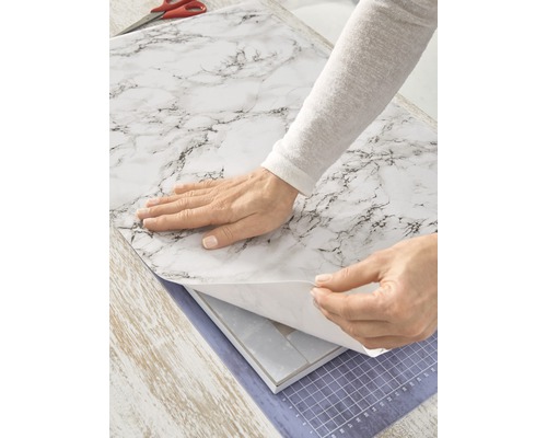 Persoon brengt zelfklevende folie in marmerlook aan