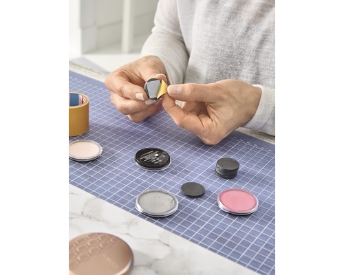 Vrouw bevestigt magneet aan cosmetische doos op een snijmat