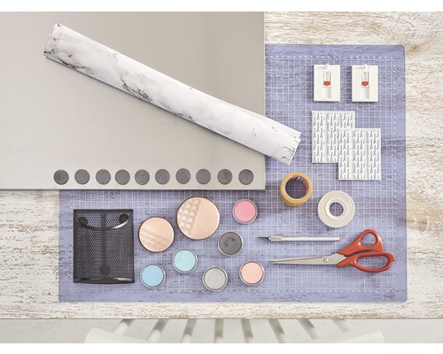 Knutselspullen op een tafel, waaronder folie, snijmat, lijm, schaar en verf