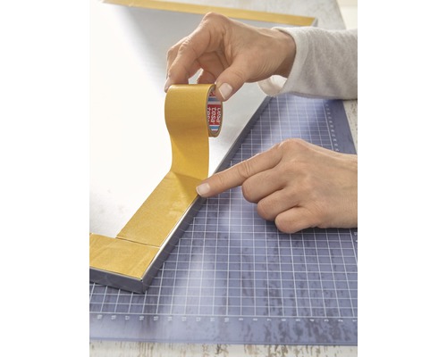 Persoon plakt dubbelzijdige tape op een spiegelframe