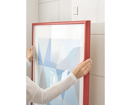 Persoon hangt ingelijste afbeelding aan de muur