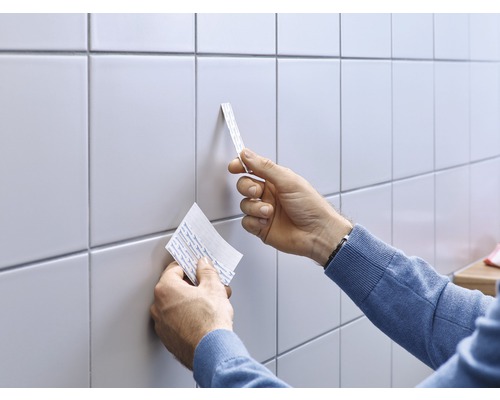 Gebruiker brengt plakstrips aan op tegels