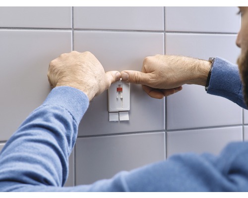 Man monteert een bevestigingssysteem aan een betegelde wand