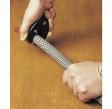 Een persoon snijdt een flexibele buis met een buissnijder.