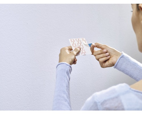 Een vrouw verwijdert de beschermfolie van een dubbelzijdige plakstrip.