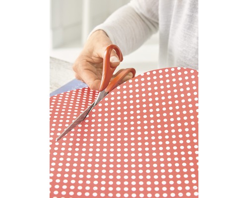 Persoon knipt papier met stippendessin met een schaar.