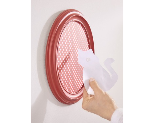 Ovale fotolijst met gestippelde achtergrond en een hand die een stuk papier met een kattenvorm aanbrengt