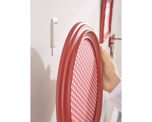 Ovale fotolijst wordt met een plakstrip aan een muur bevestigd