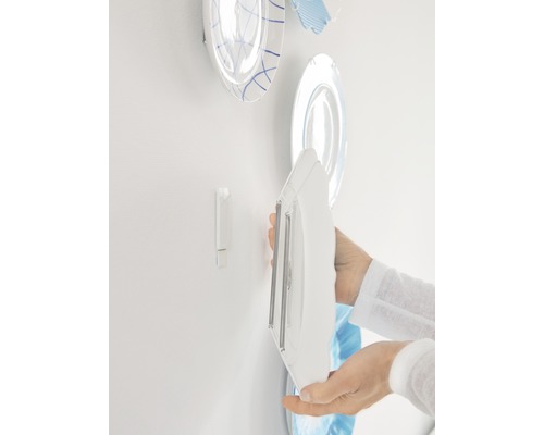 Persoon bevestigt bord met bordenhanger aan de muur