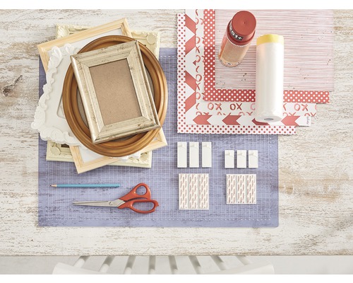 Decoratieve scène met fotolijsten, hobby papier, plakstrips, schaar en potlood op een snijmat