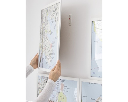 Vrouw bevestigt ingelijste plattegrond aan de muur
