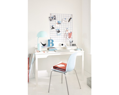 Bureau met stoel, bureaulamp, prikbord en decoratieve elementen in een lichte ruimte.