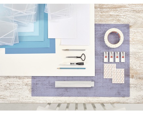 Creatieve materialen voor fotolijsten op een tafel: fotolijsten, papier, snijgereedschap, krijtstift, potlood, plakband, fotolijsthaken en plakstrips