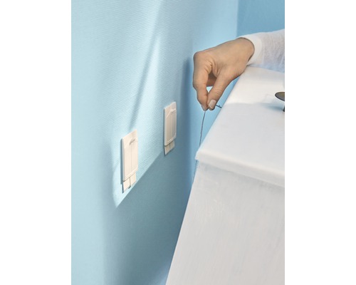 Montage van twee zelfklevende haken op een muur met een persoon die een touw vasthoudt.