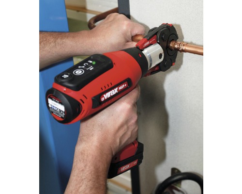 Een persoon gebruikt een accupersgereedschap om een koperen buis te persen.