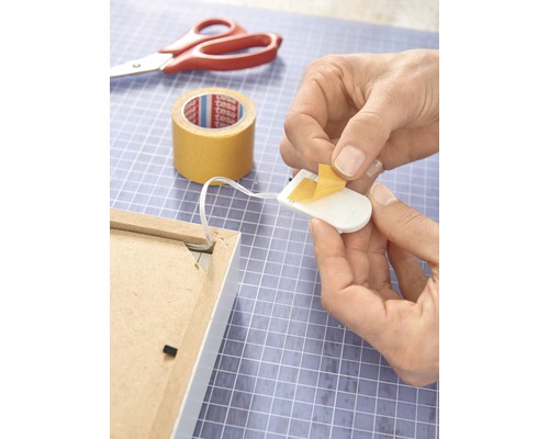 Een lichtsnoer met dubbelzijdige tape aan de achterkant van een fotolijst bevestigen