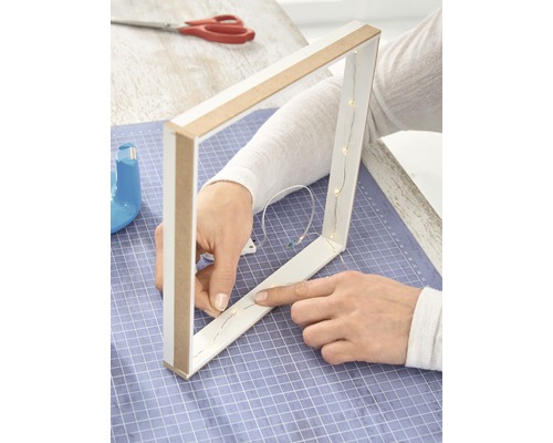 Persoon bevestigt een lichtsnoer aan een driehoekig houten frame