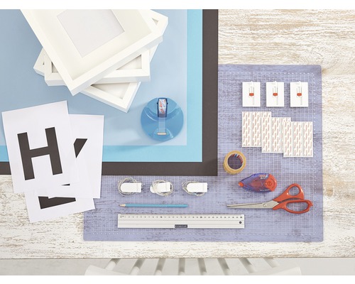 Knutselmaterialen met fotolijsten, letters, plakband, schaar, potlood en snijmat