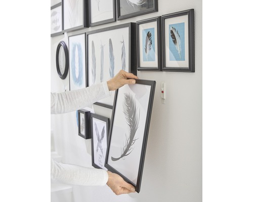 Persoon hangt fotolijst aan de muur