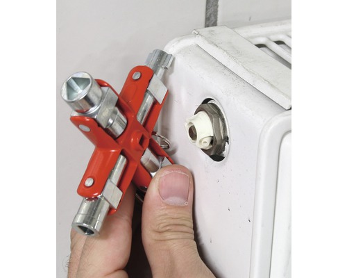 Een man gebruikt een radiateursleutel op een radiator.