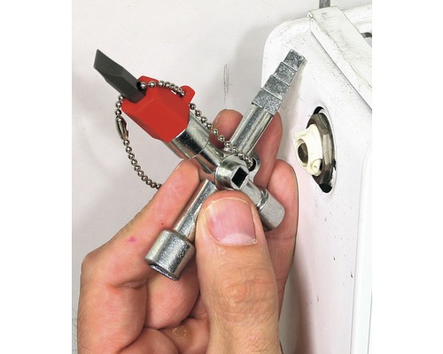 Een man gebruikt een multifunctionele sleutel om een radiator te ontluchten.