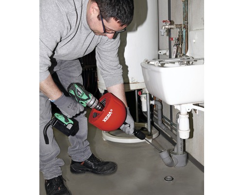 Een loodgieter gebruikt een ontstoppingsveer om een afvoerpijp te ontstoppen.