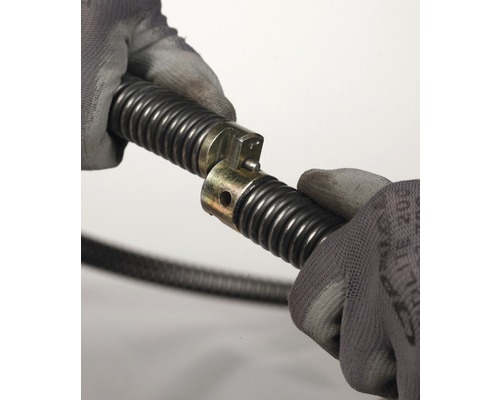 Twee handen met handschoenen verbinden een ontstoppingsveer.