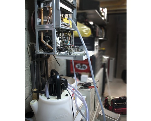 Geopende verwarmingsketel wordt gereinigd met een spoelpomp.