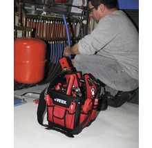 Een installateur werkt aan een verwarmingssysteem met een gereedschapstas van het merk Virax.