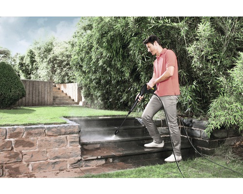 Man reinigt buitentrap met hogedrukreiniger in de tuin.