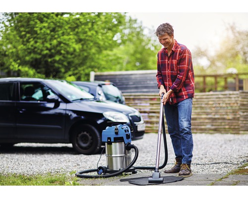 Man stofzuigt een automat met een nat- en droogzuiger voor een auto.
