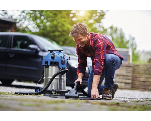 Man gebruikt een reinigingsstofzuiger om het interieur van een auto buiten schoon te maken.