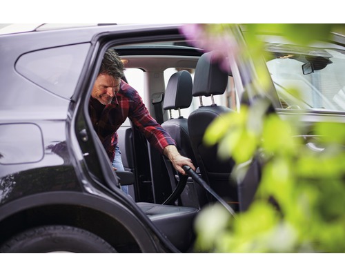 Man zuigt het interieur van een auto met een stofzuiger