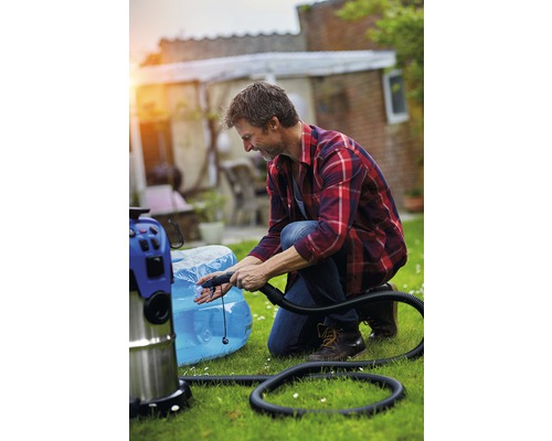 Een man knielt in de tuin en pompt een zwembad op met een alleszuiger.