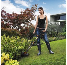 Vrouw werkt met een gazontrimmer in de tuin.