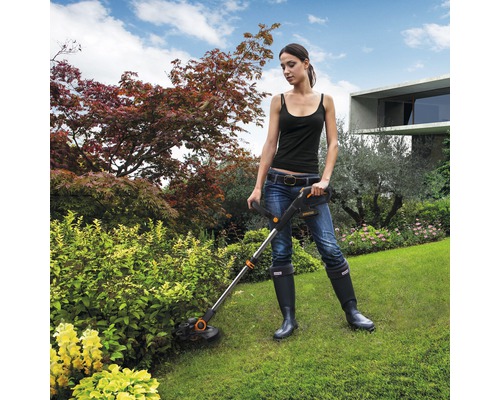 Vrouw werkt met een gazontrimmer in de tuin.