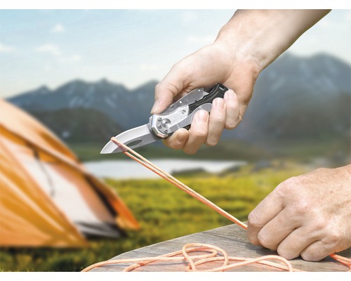 Persoon snijdt touw met een zakmes in de natuur.