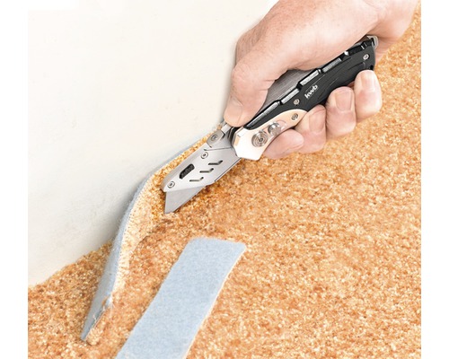 Een hand snijdt een tapijt door met een universeel mes