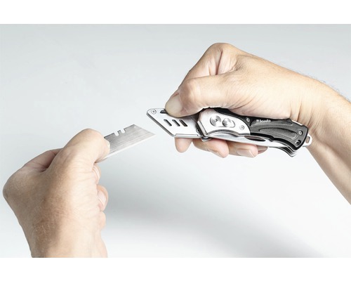 Een hand vervangt het mes van een stanleymes